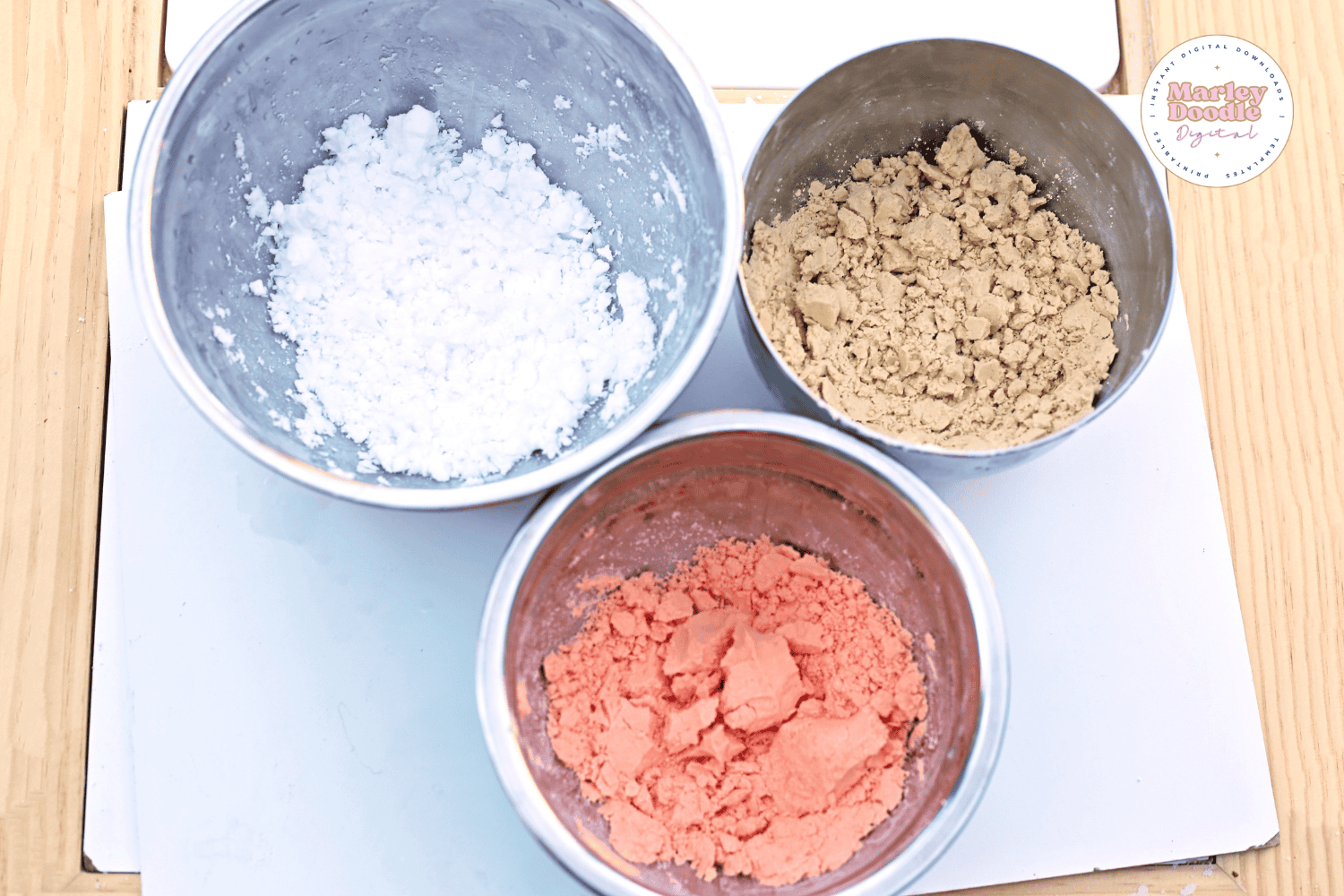 Three bowls with white, tan, and pink cloud dough mixtures.