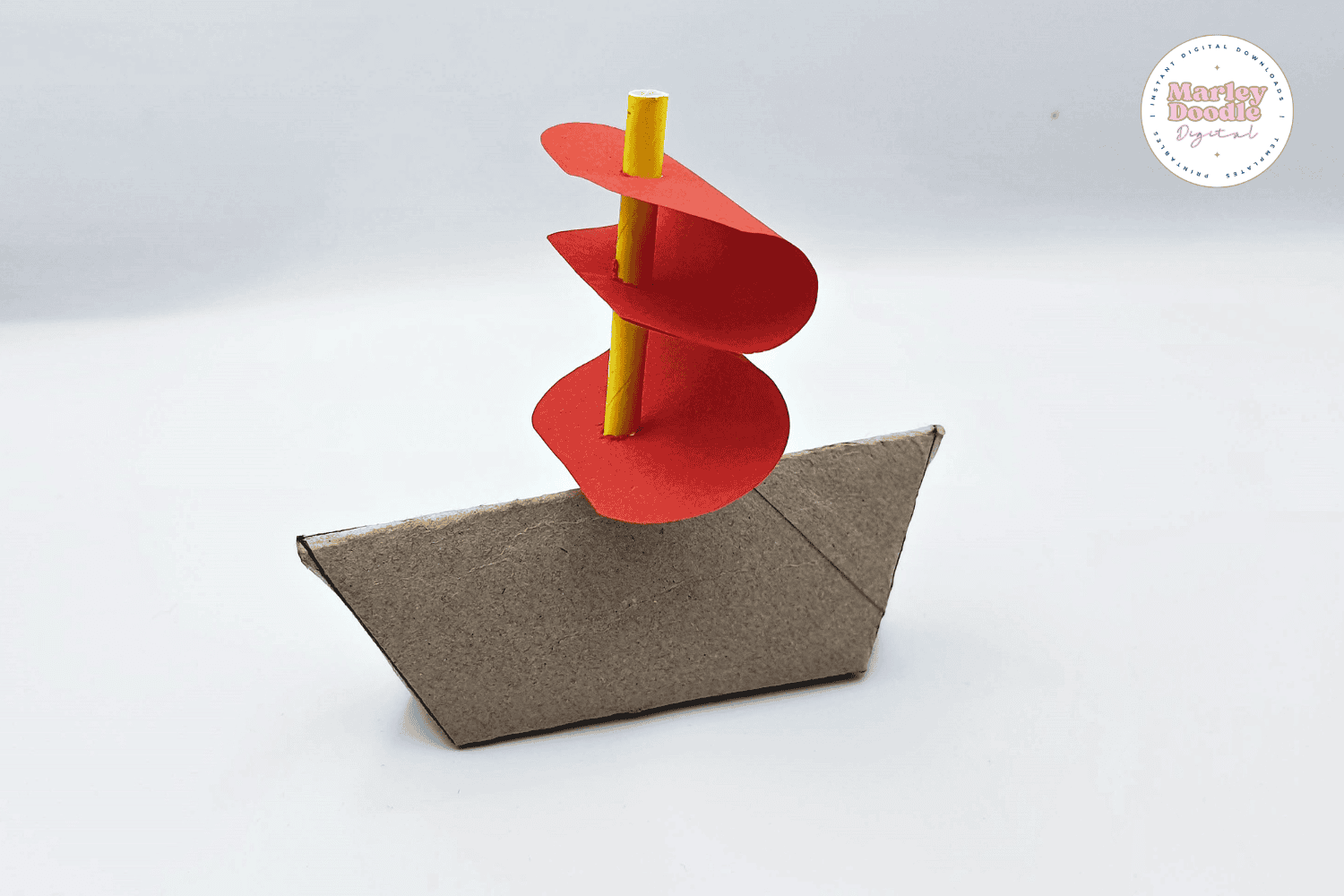 Toilet paper roll boat with red sails and yellow mast.