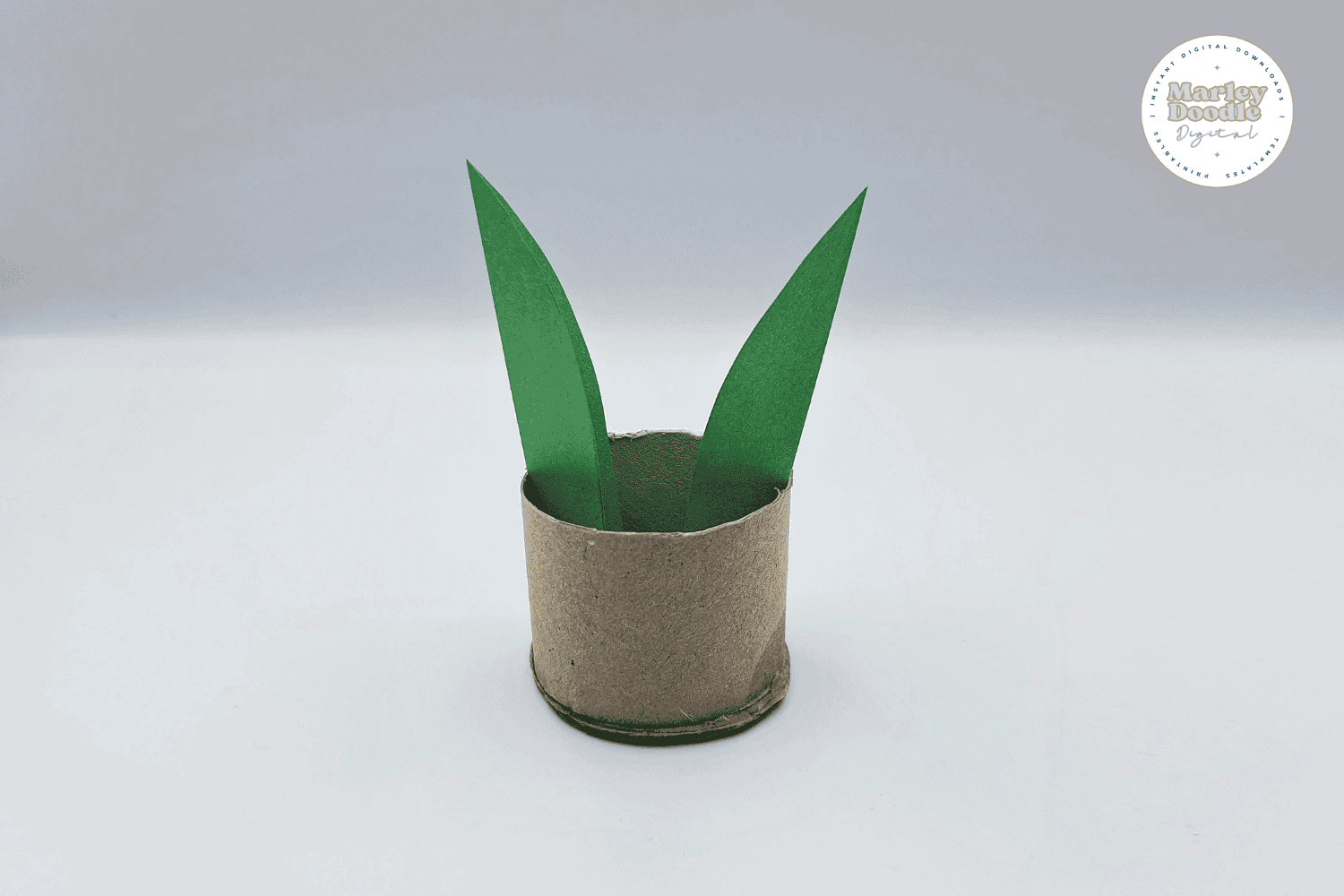 Adding first leaves to toilet paper roll plant craft.