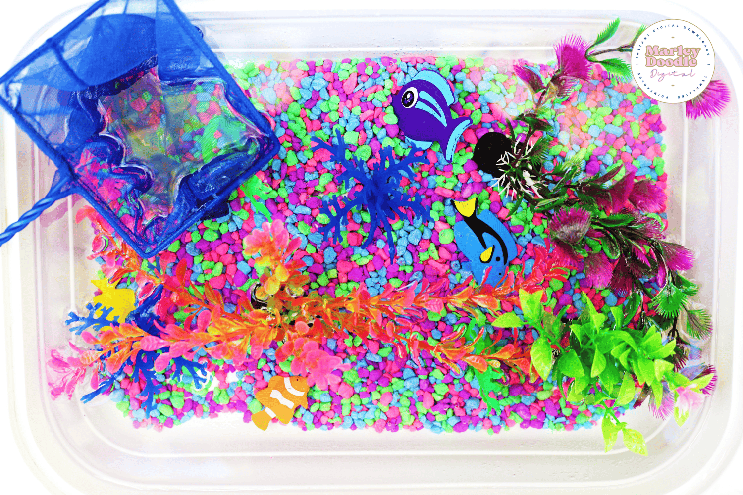 Top view of aquarium sensory bin with toy fish and plants.