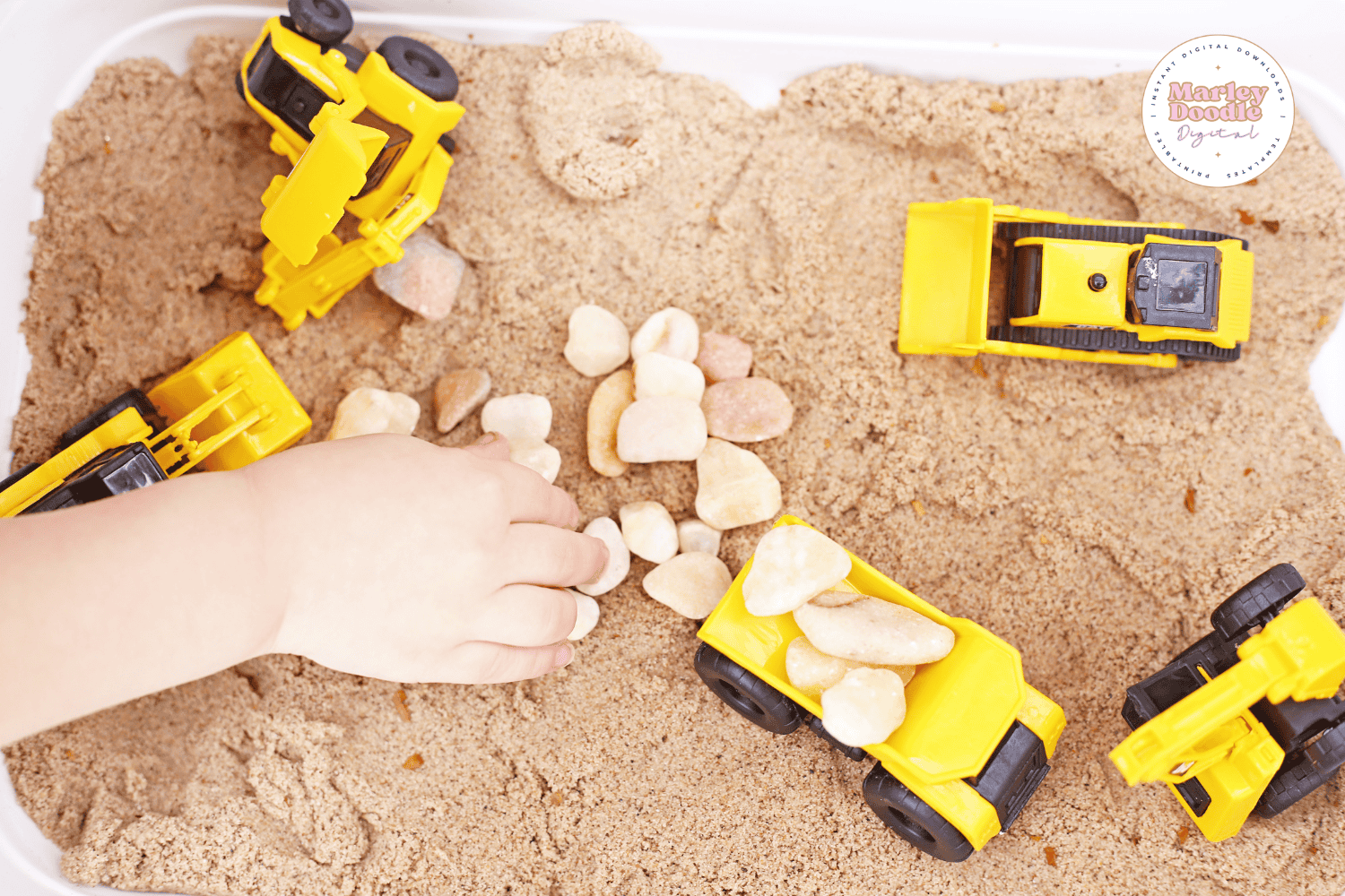 Child playing with rocks and trucks in sensory bin.