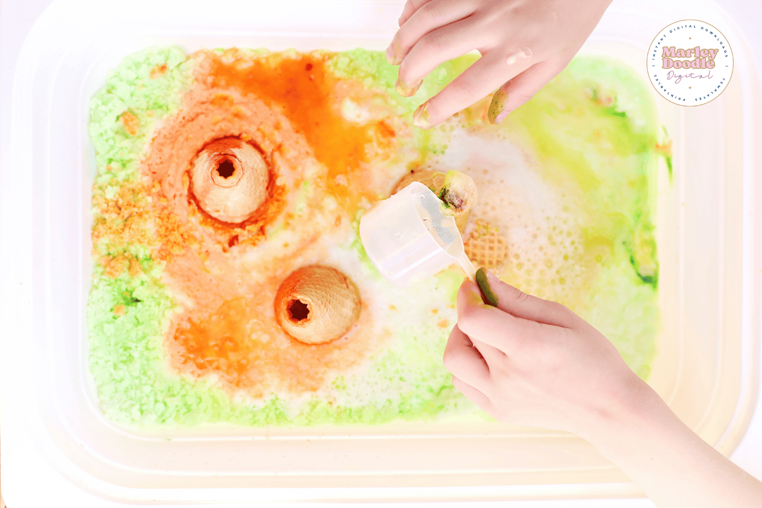 Child pouring vinegar into fizzy volcano sensory bin.