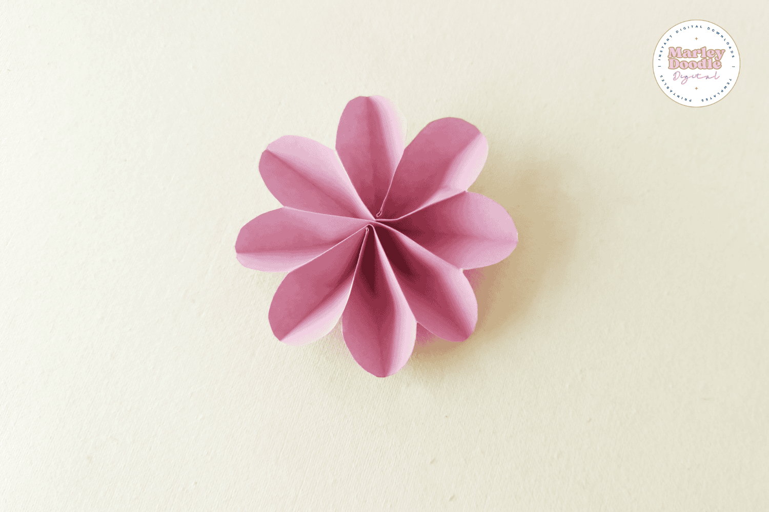 Folded pink paper flower for DIY wreath craft.