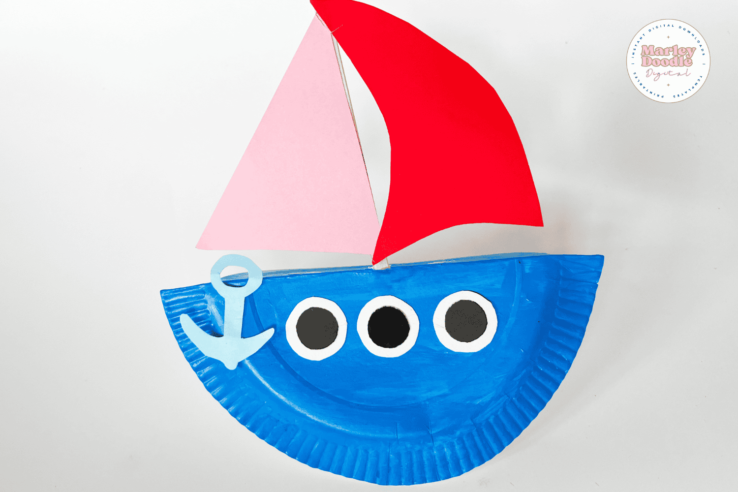 Finished rocking boat craft with colorful sails attached.