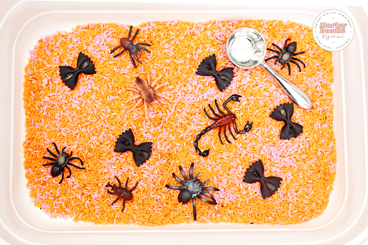 Halloween sensory bin with orange rice, black pasta, and toy spiders and scorpions