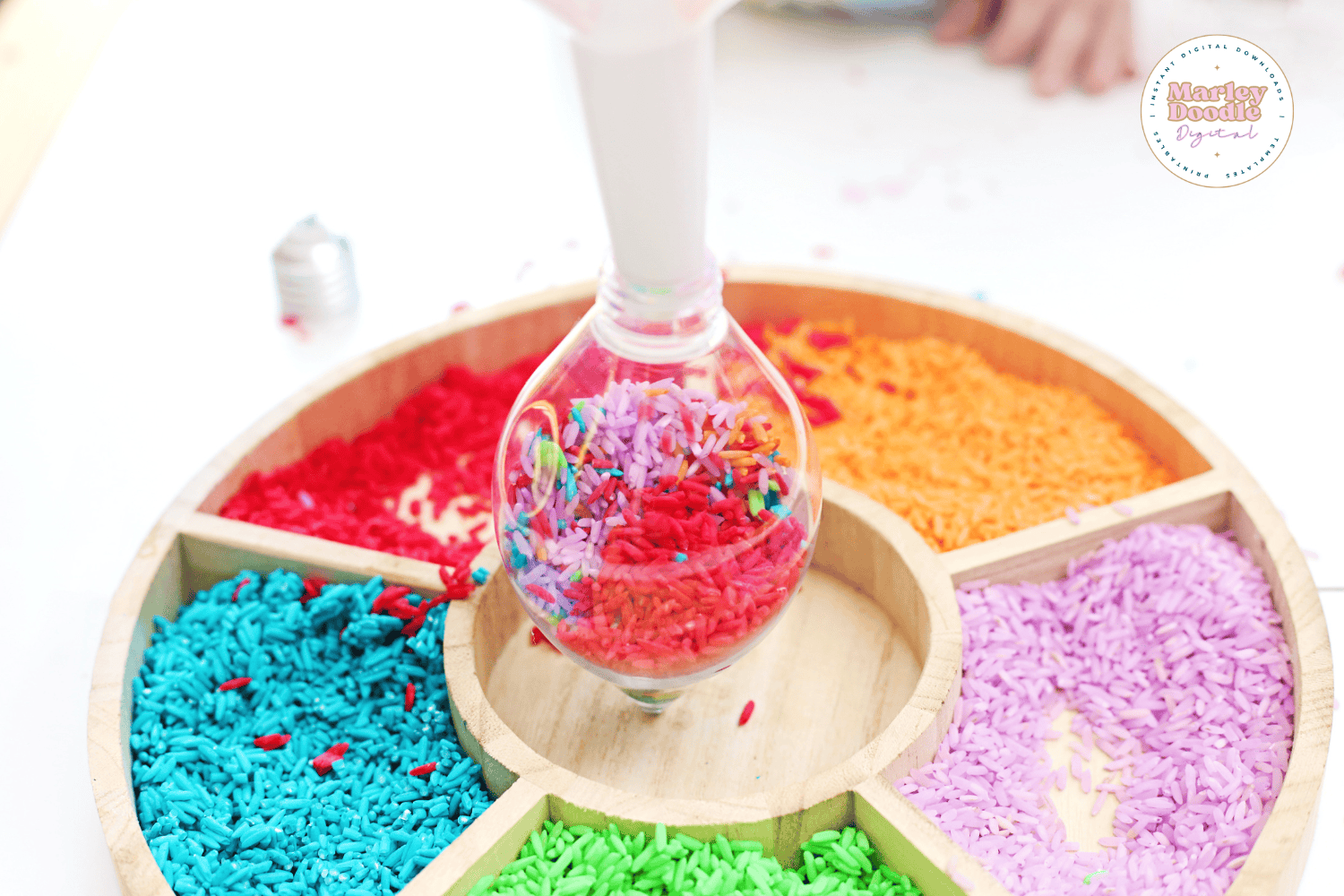 Filling ornament with rainbow rice for Christmas lights sensory tray